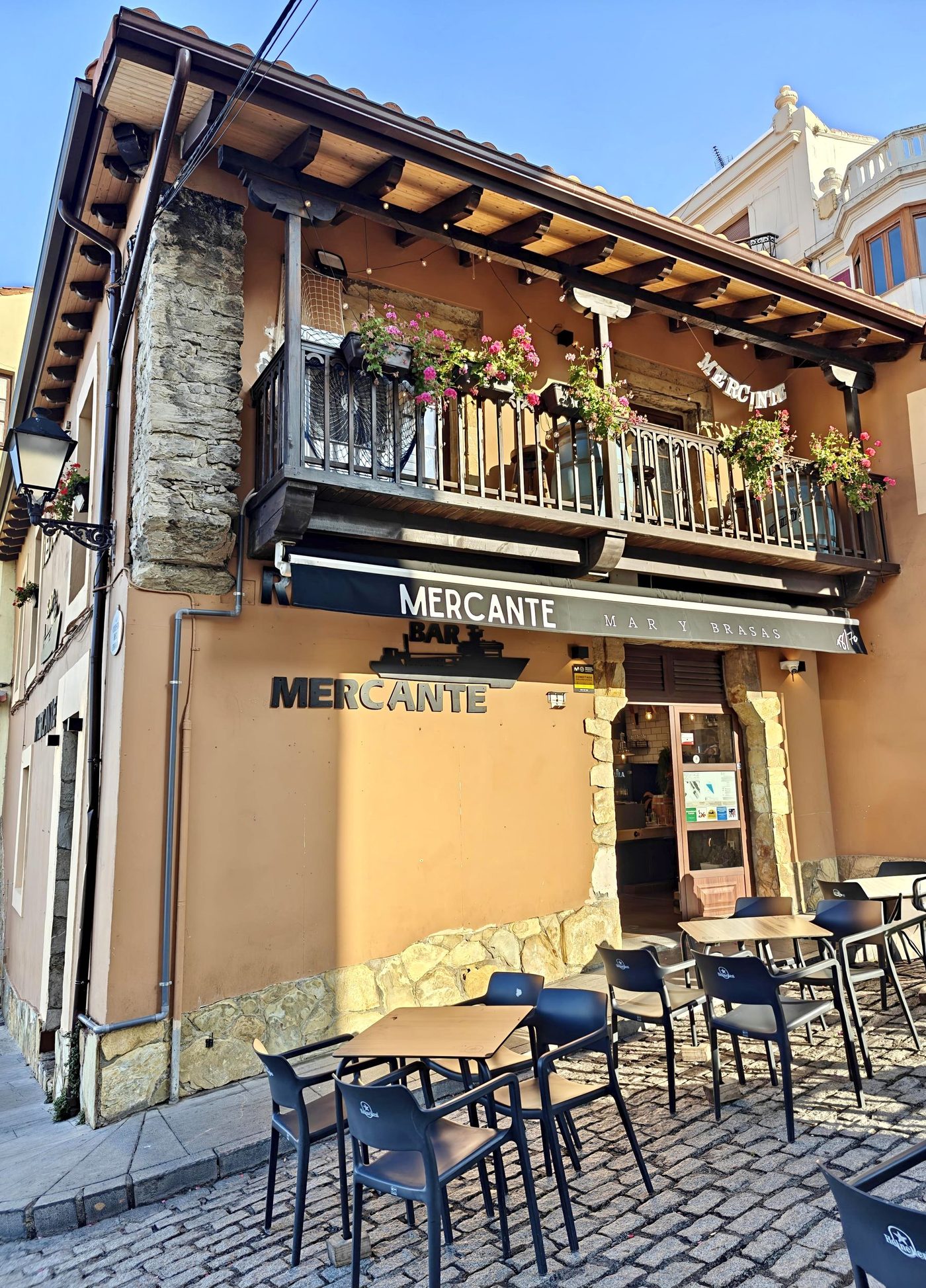 Fachada del Mercante con balcón de flores y rótulo Mar y Brasas