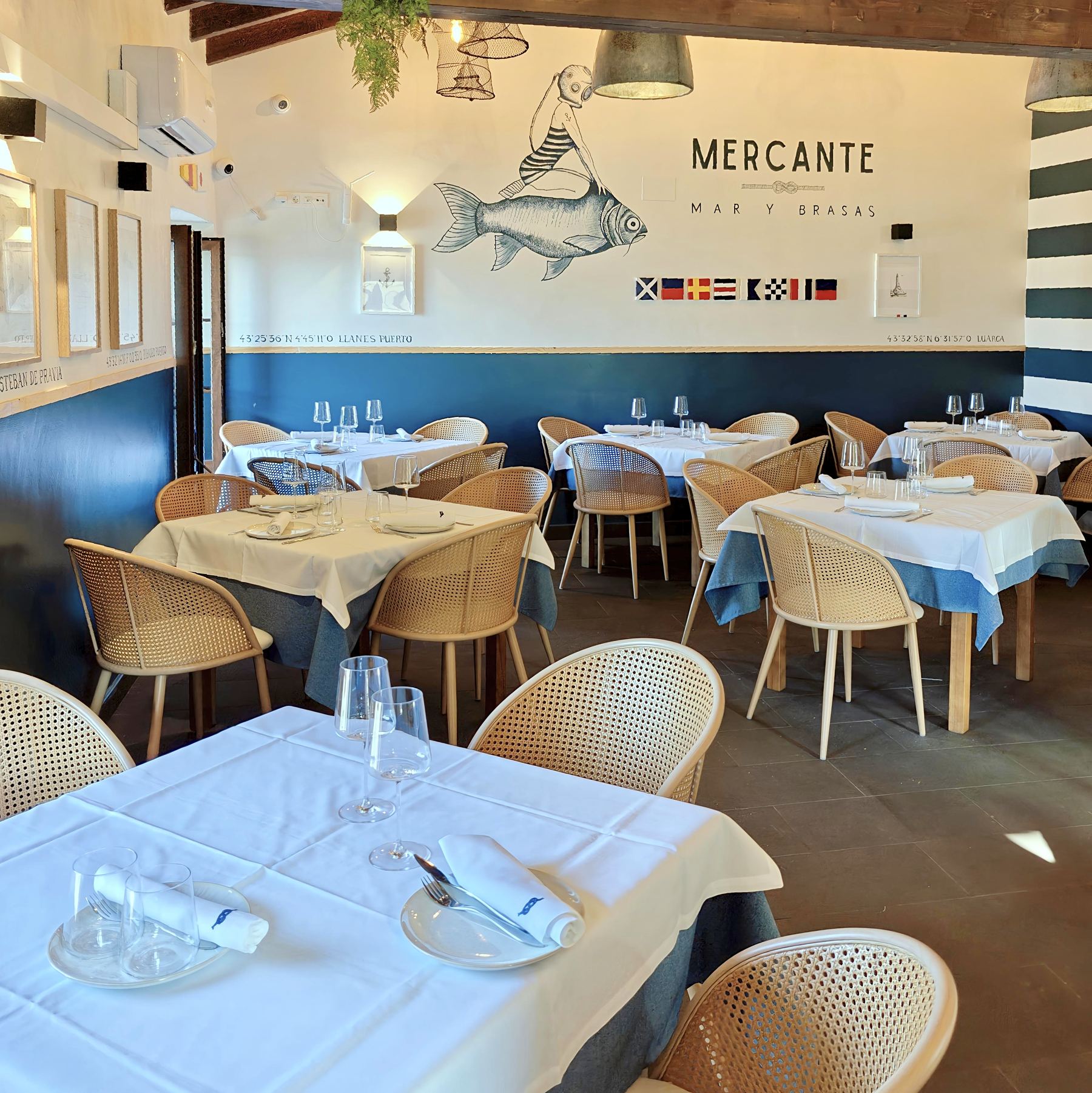 Comedor del Mercante con mural náutico, banderas de señales y mesas dispuestas